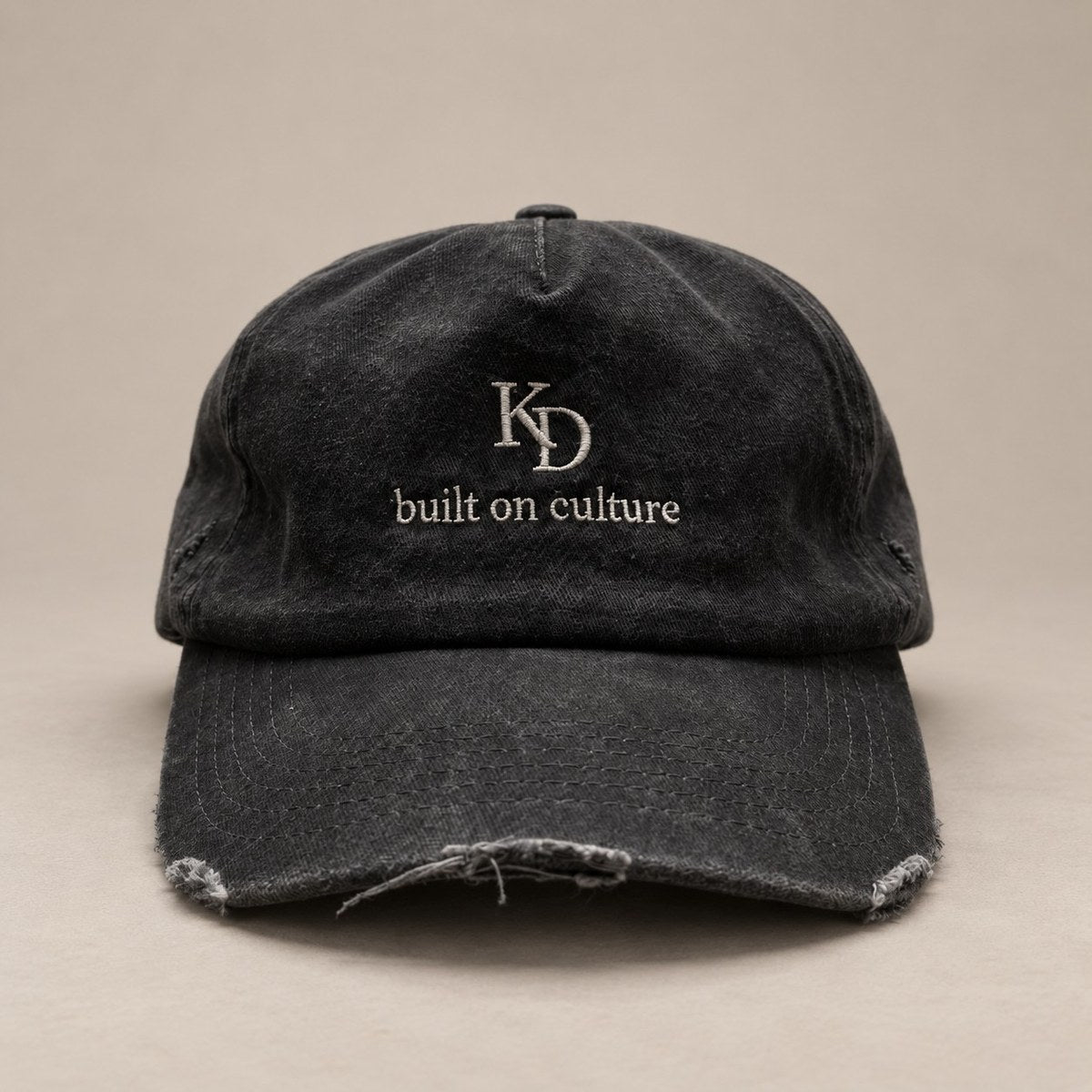 KRWN DISTRICT The Culture Washed Black — vintage 5-panel cap, stone-washed black cotton with cream KD monogram and built on culture embroidery, front view (AI-generated)