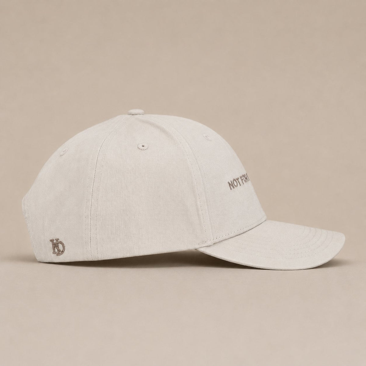 KRWN District The Code — Stone Off White, side view with embroidered KD emblem (AI-generated)